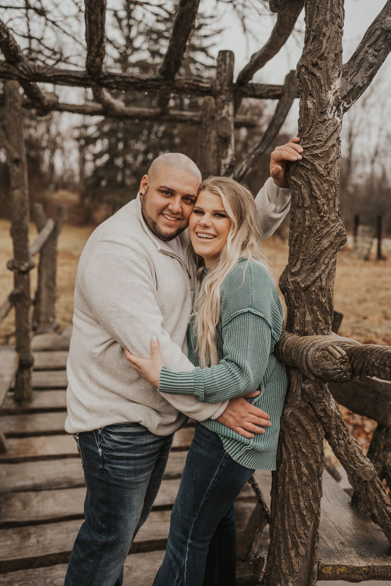 Couple embracing by rustic wooden fence during autumn photoshoot in Irish Hill's Michigan.