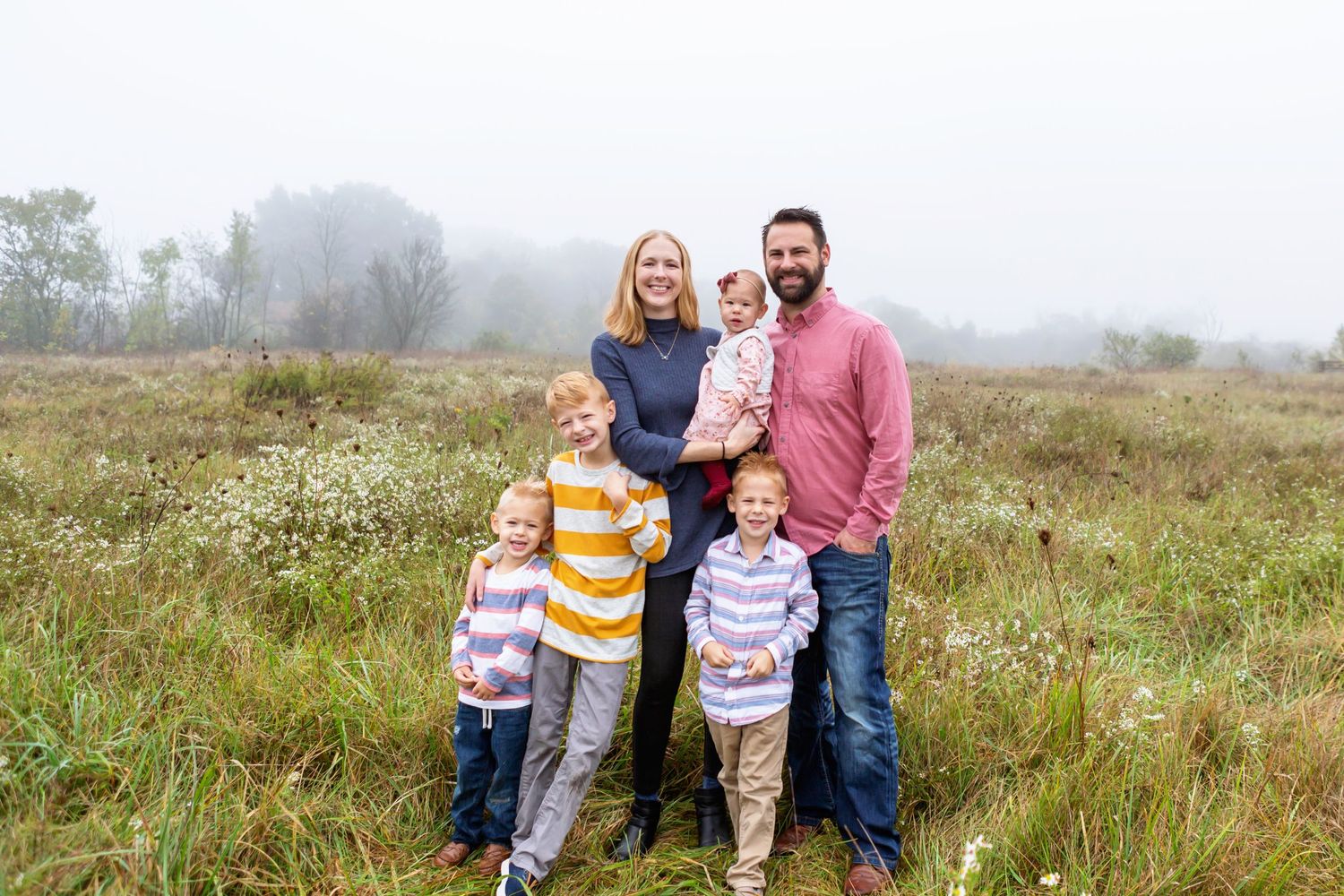 family of four standing in a fall field