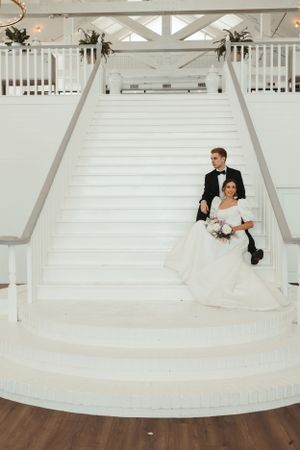 Elegant white staircase with decorative railings and floral arrangements in a wedding venue.