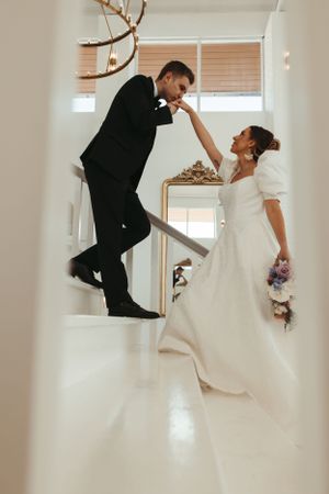 Wedding couple posing playfully on a white staircase.