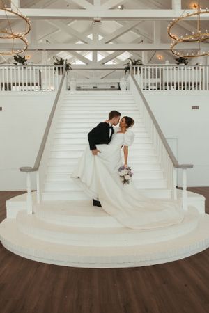 Romantic wedding couple sharing a kiss on grand white stairs.