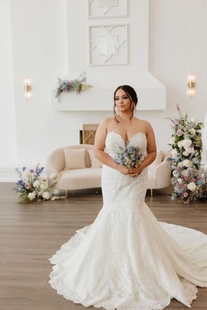Bridal portrait in a white room with elegant floral decor.