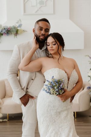 Wedding couple posing in elegant white room with pastel floral decor.