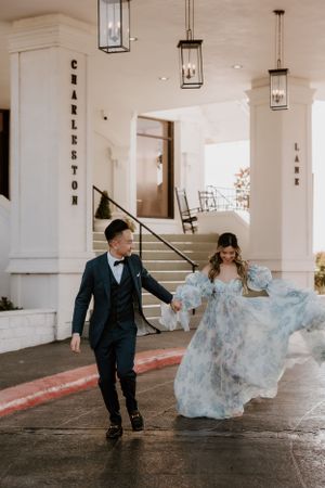 Couple in formal attire strolls under Charleston venue's lantern-lit entrance.