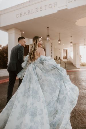 Couple poses at Charleston venue entrance with flowing light blue wedding dress.