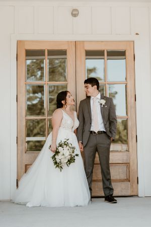 Stylish wedding couple posed against vintage French doors in natural light.