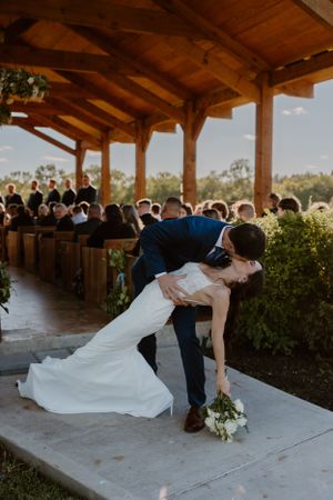 A dramatic wedding dip pose during the ceremony in a rustic wooden chapel.