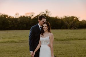 Sunset portrait of wedding couple in open field with warm evening light.