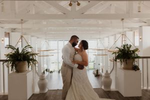 Intimate wedding moment in bright white venue with hanging plants and natural lighting.