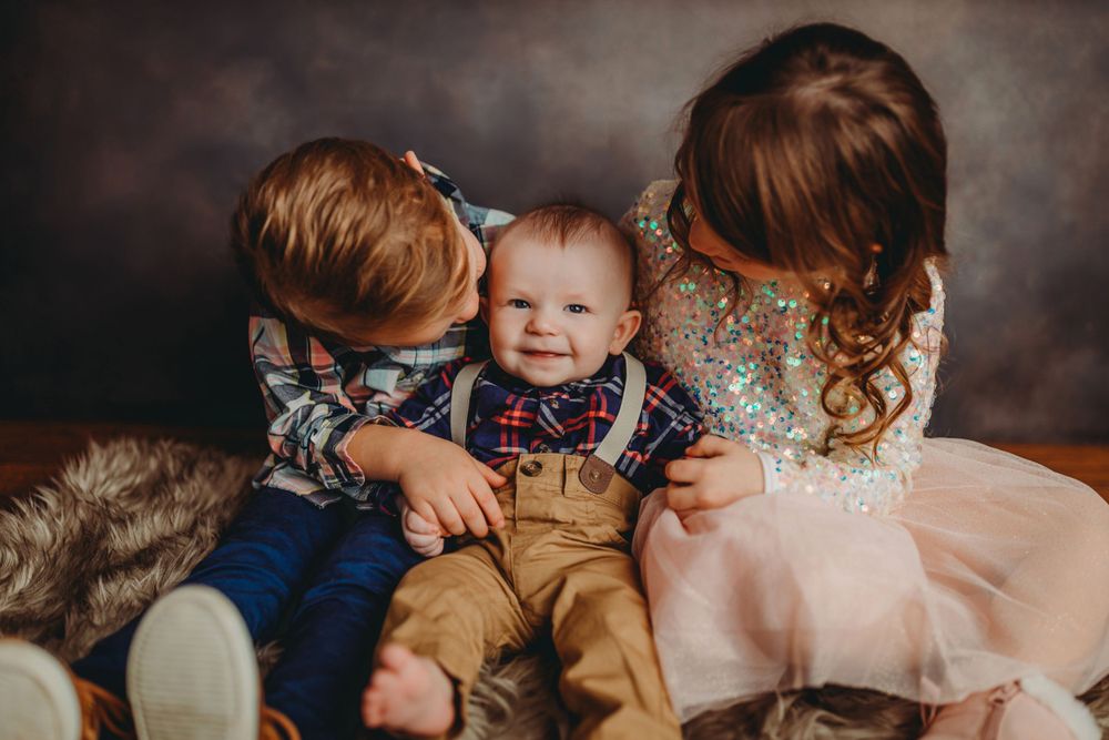 Studio portrait of three children sitting together against dark background.