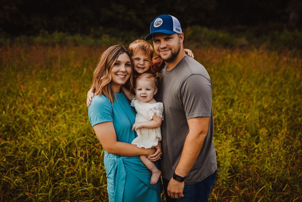 Happy family portrait outdoors in a golden field during sunset.
