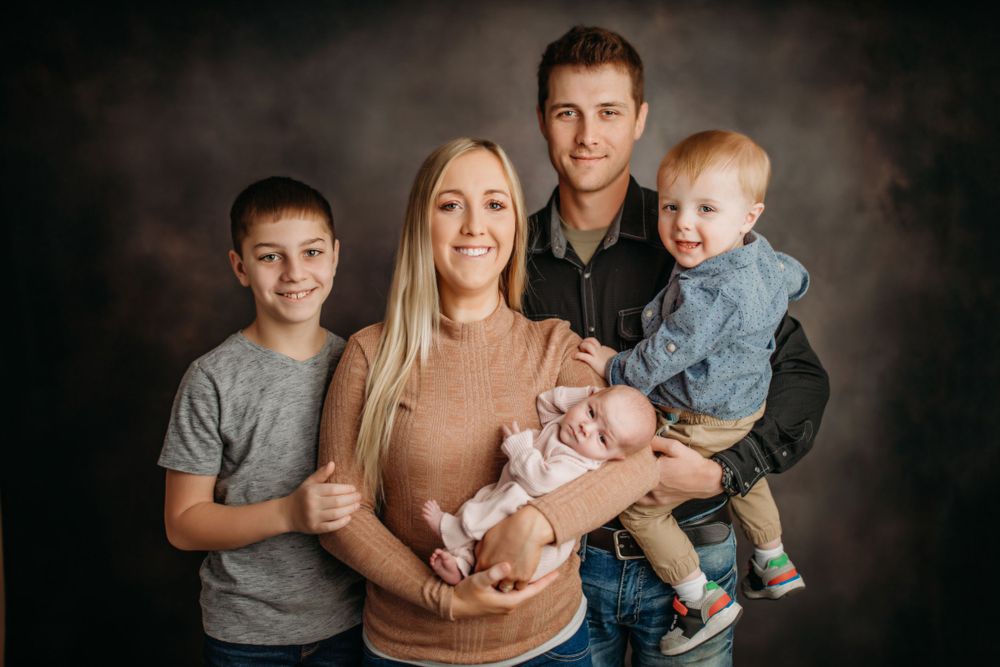 A loving family portrait with multiple children in a professional studio setting against a dark background.