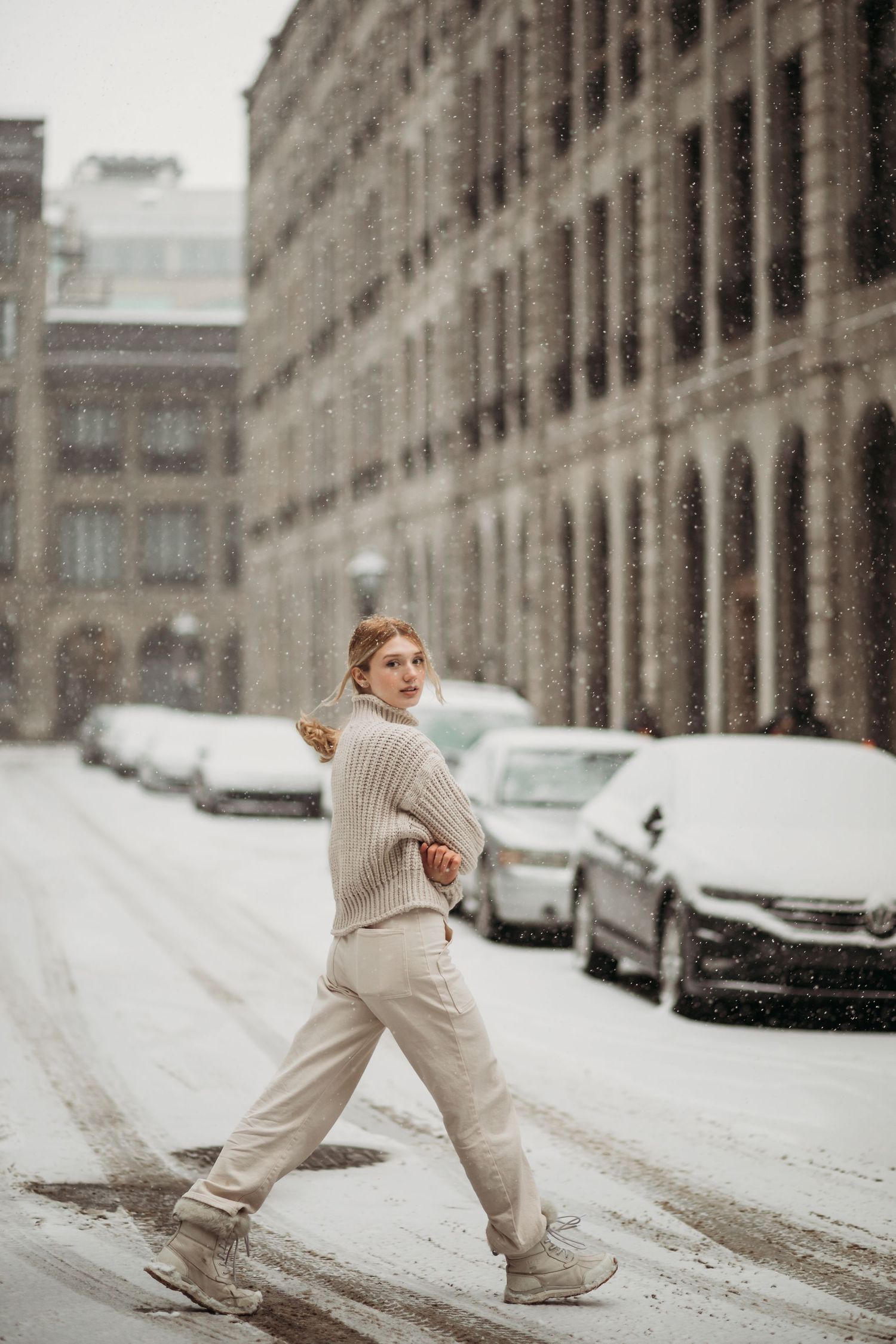 Winter street style photo with person in beige sweater walking through snowy city.