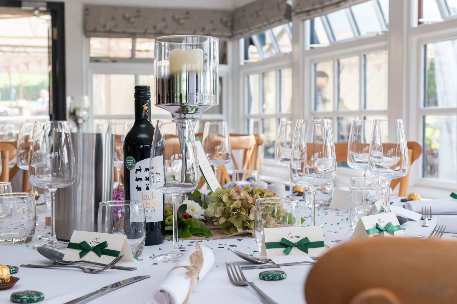 Elegant wedding reception table setting with wine glasses, bottles and floral centerpieces.