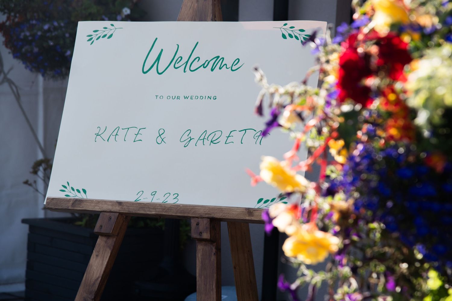 Welcome sign with floral decorations displayed on an easel.