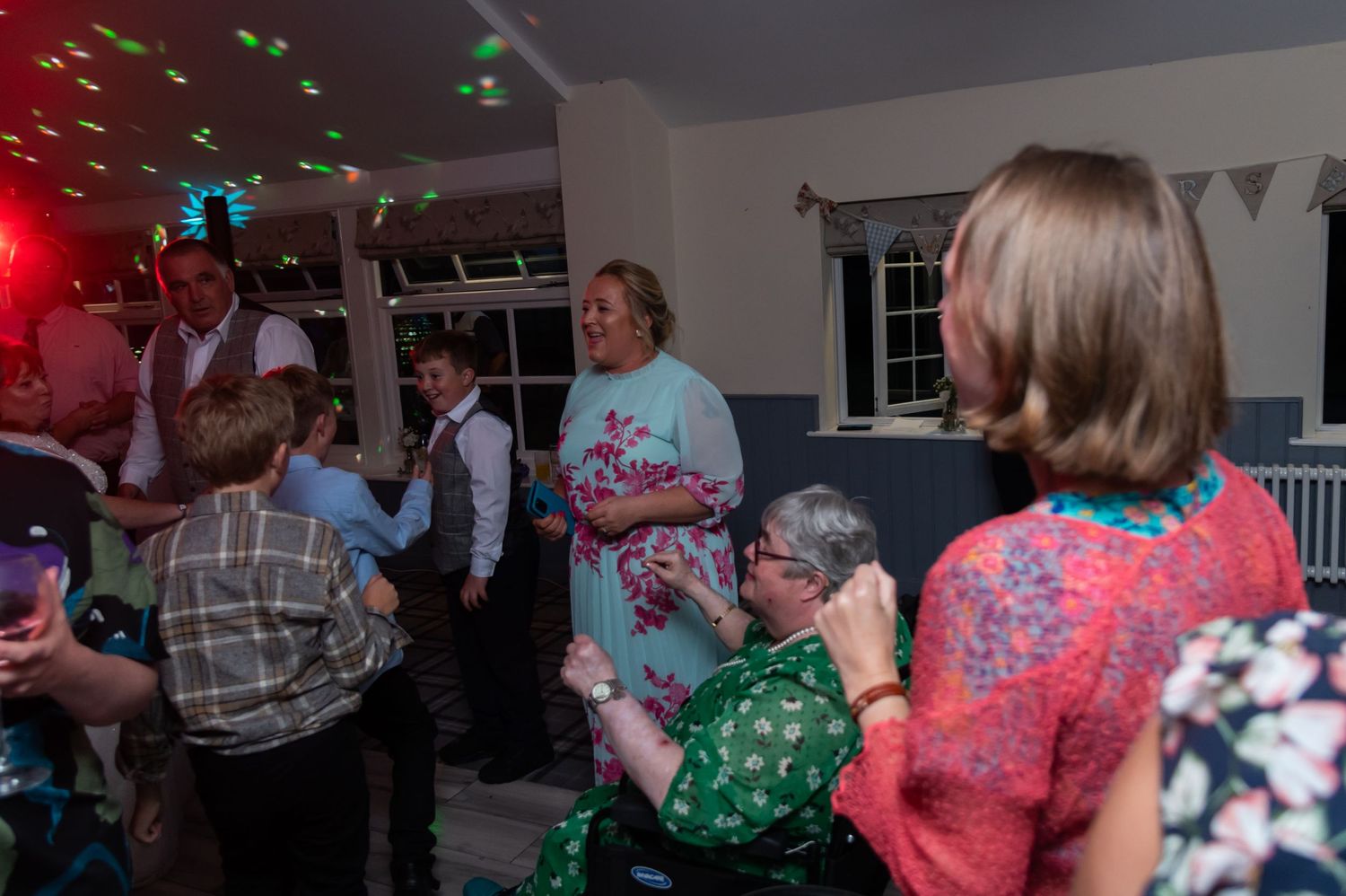 Wedding reception dance floor with colorful lighting and guests dancing.