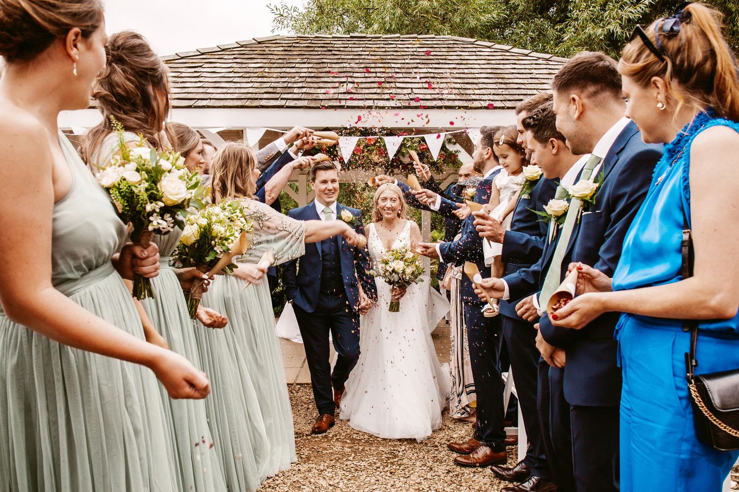 Wedding party and guests line up outdoors for a celebratory confetti toss.