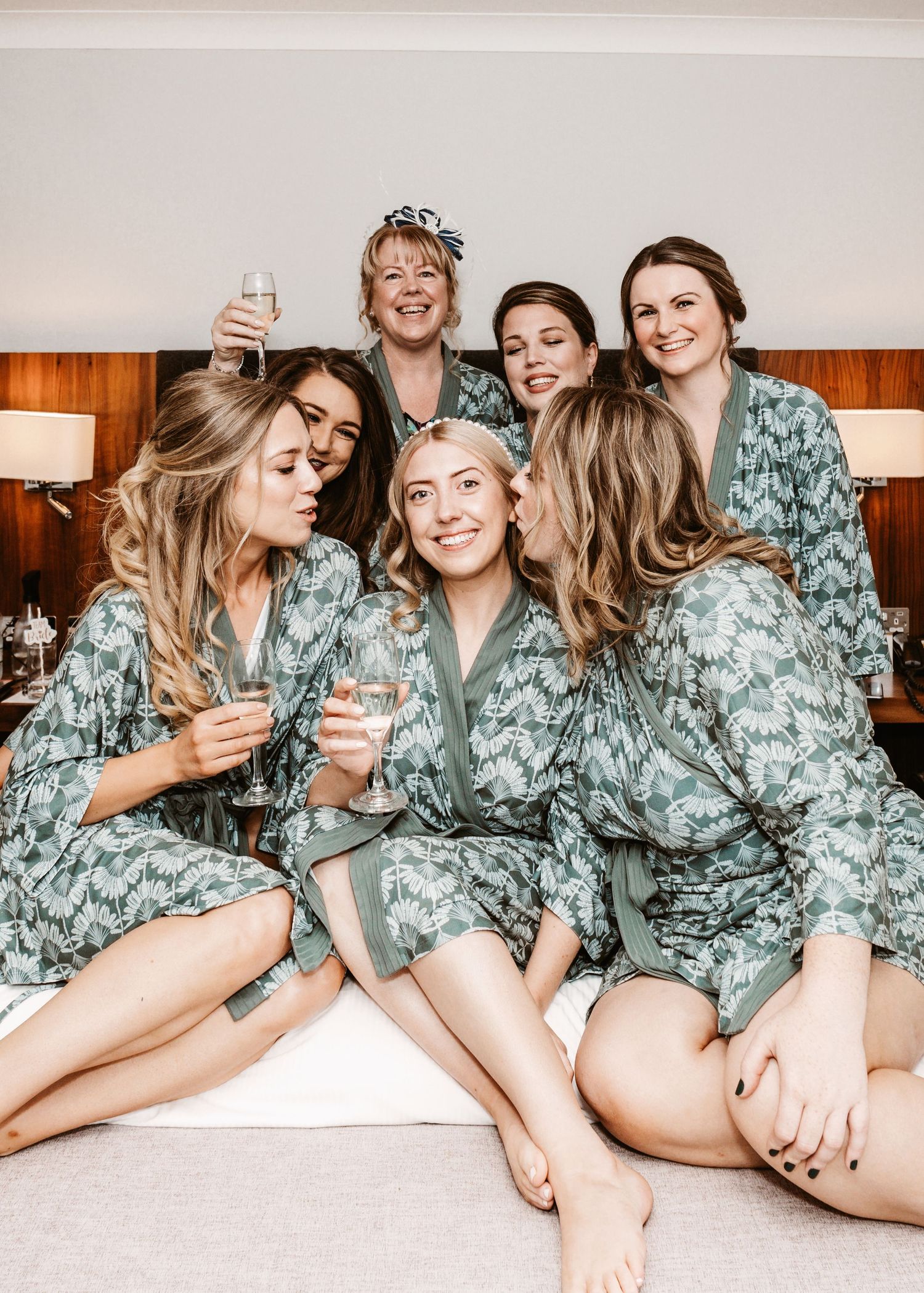 Group wearing matching floral robes celebrating during wedding preparations.