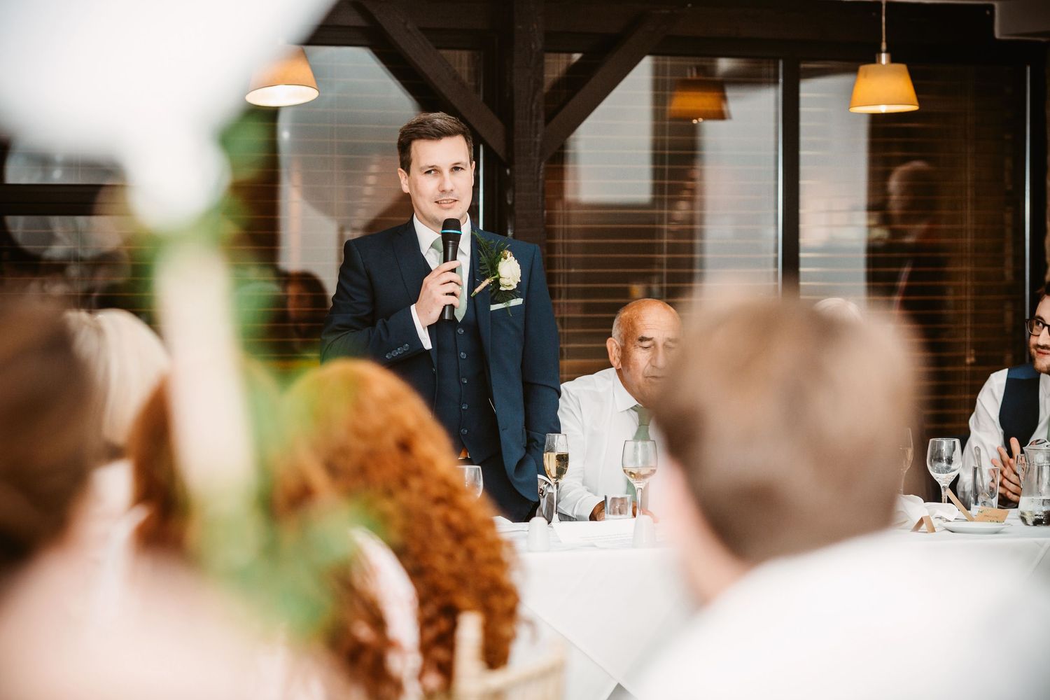 Wedding speech being delivered at reception with guests listening attentively.