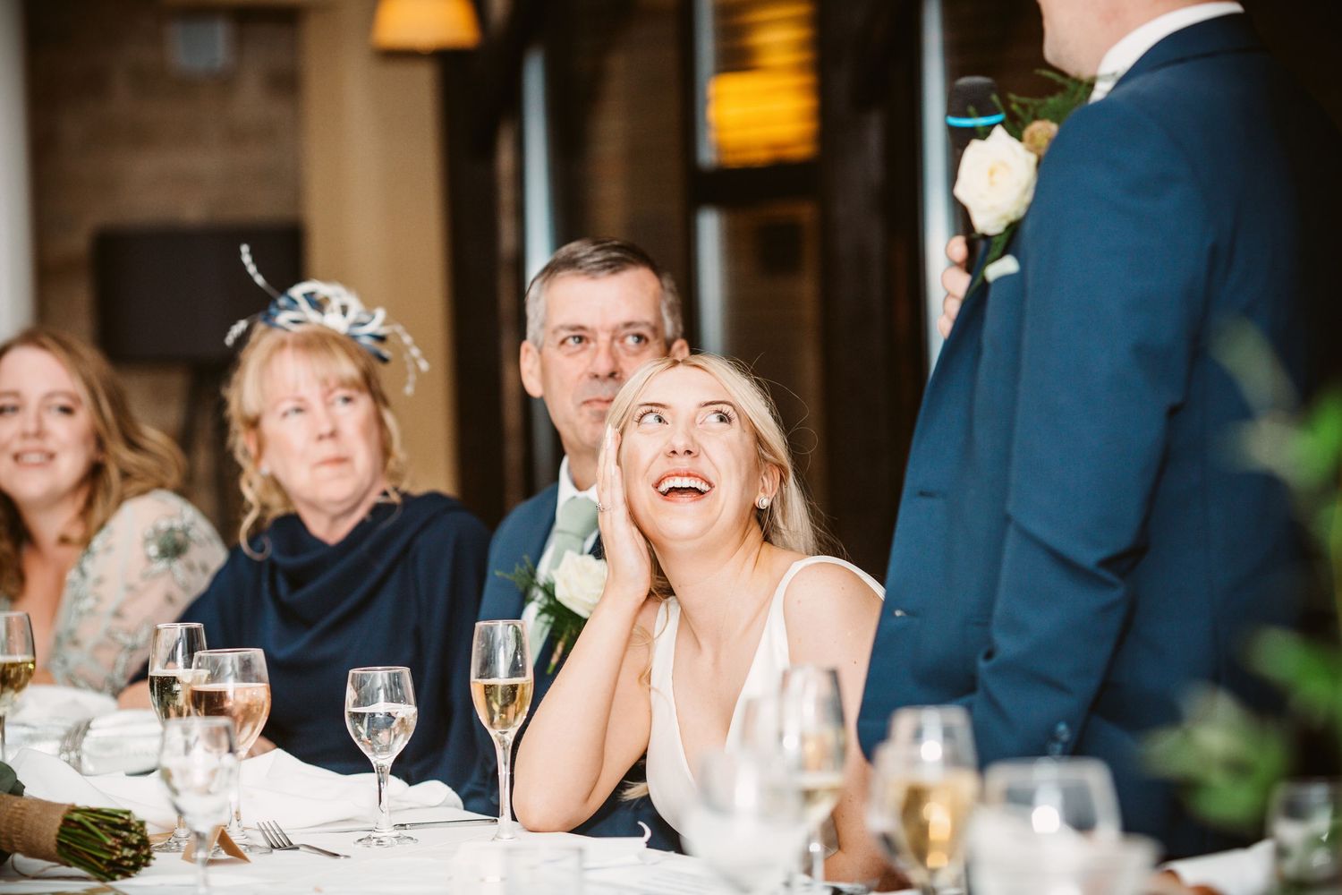 Reception guests react emotionally to wedding speech at dinner table.