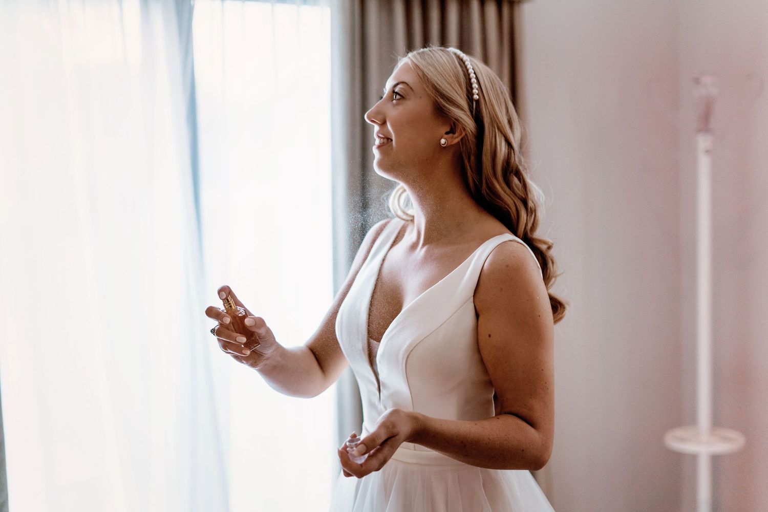 Elegant moment captured during wedding preparation by window light.