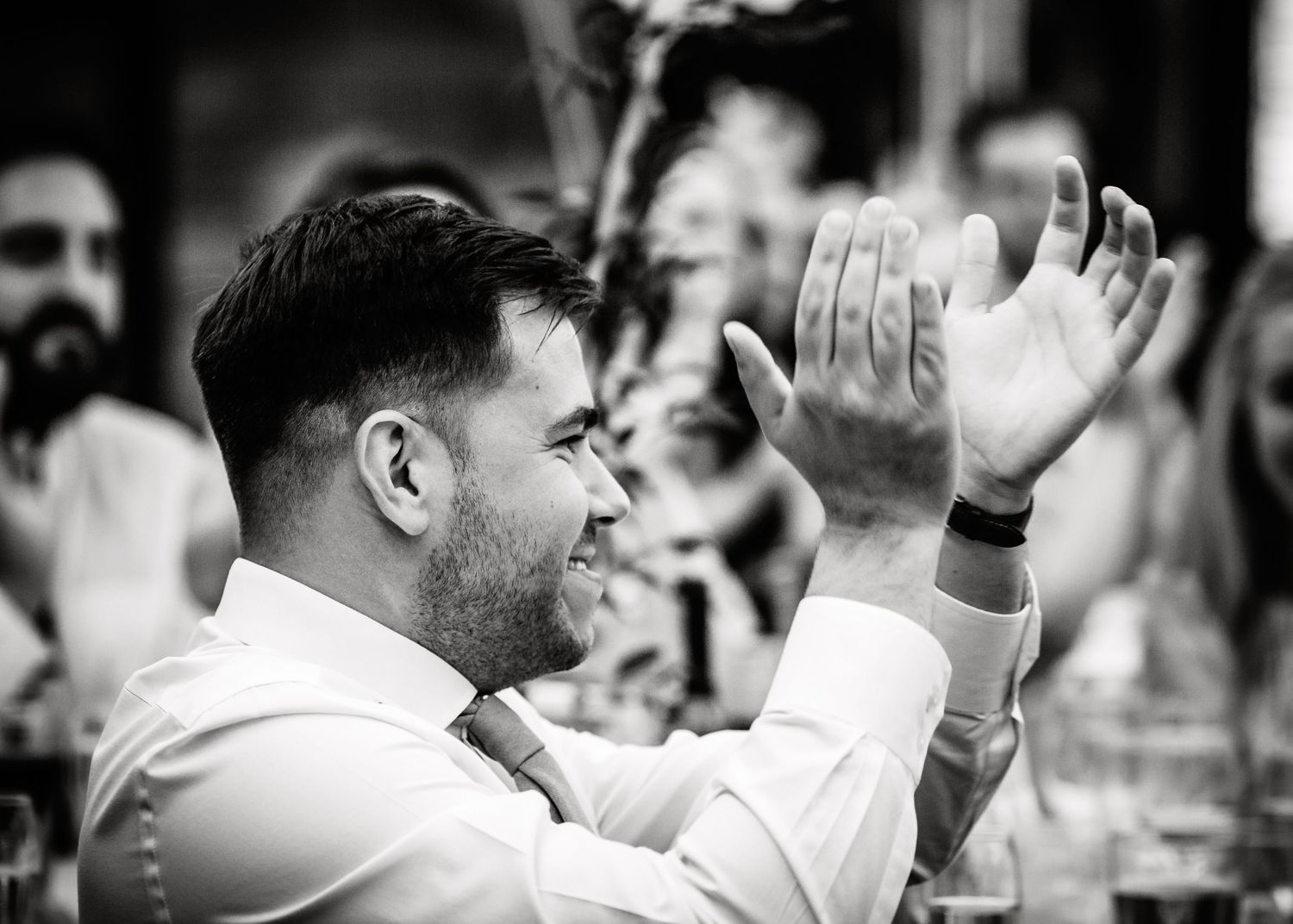 Guest claps enthusiastically during wedding reception in black and white photograph.