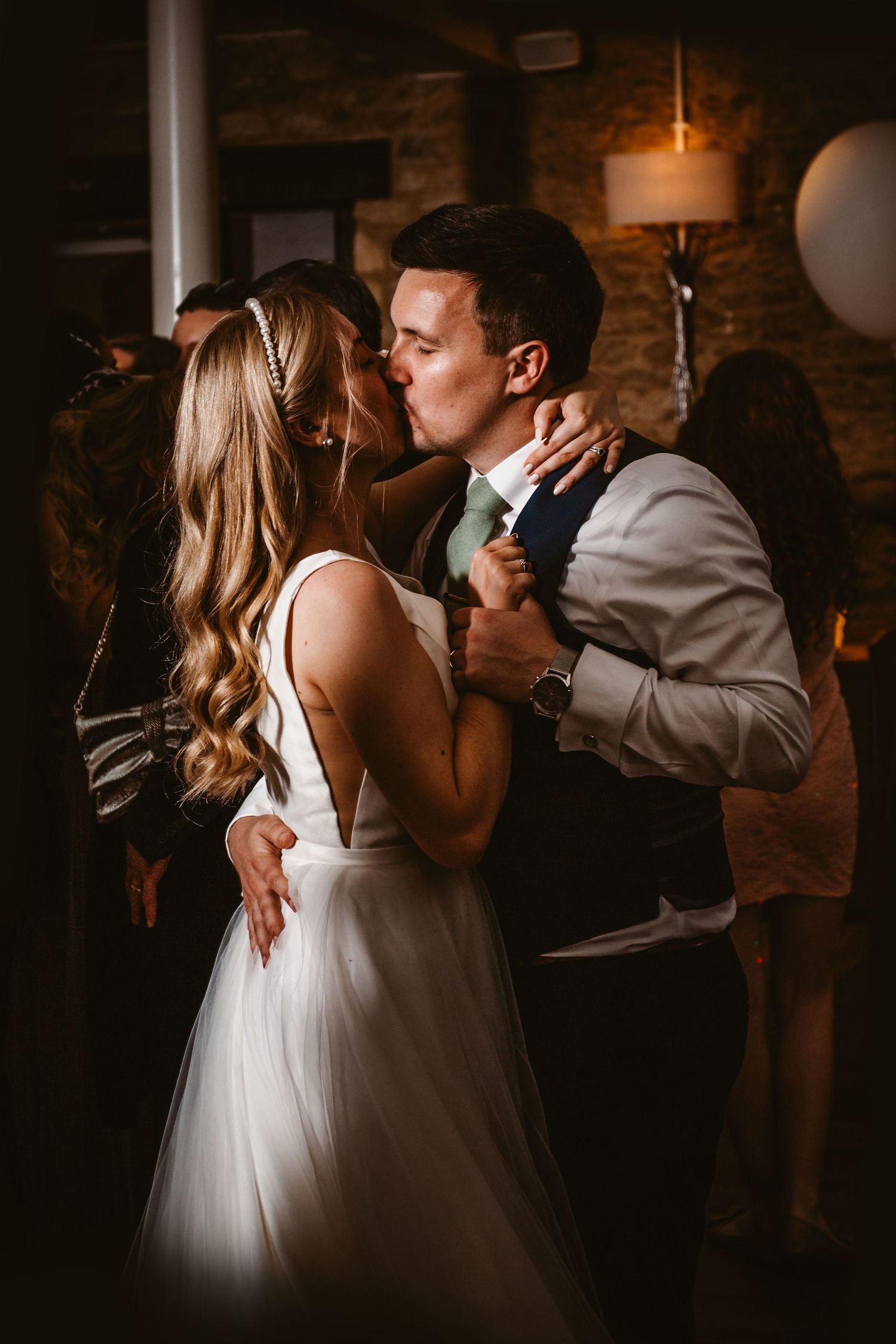 A romantic first dance moment between newlyweds in an intimate, warmly lit indoor venue with rustic brick walls.