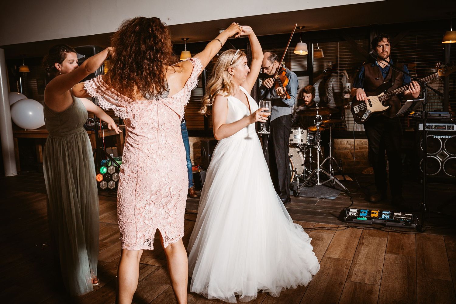Wedding celebration with dancing and live band performance in a rustic indoor venue.