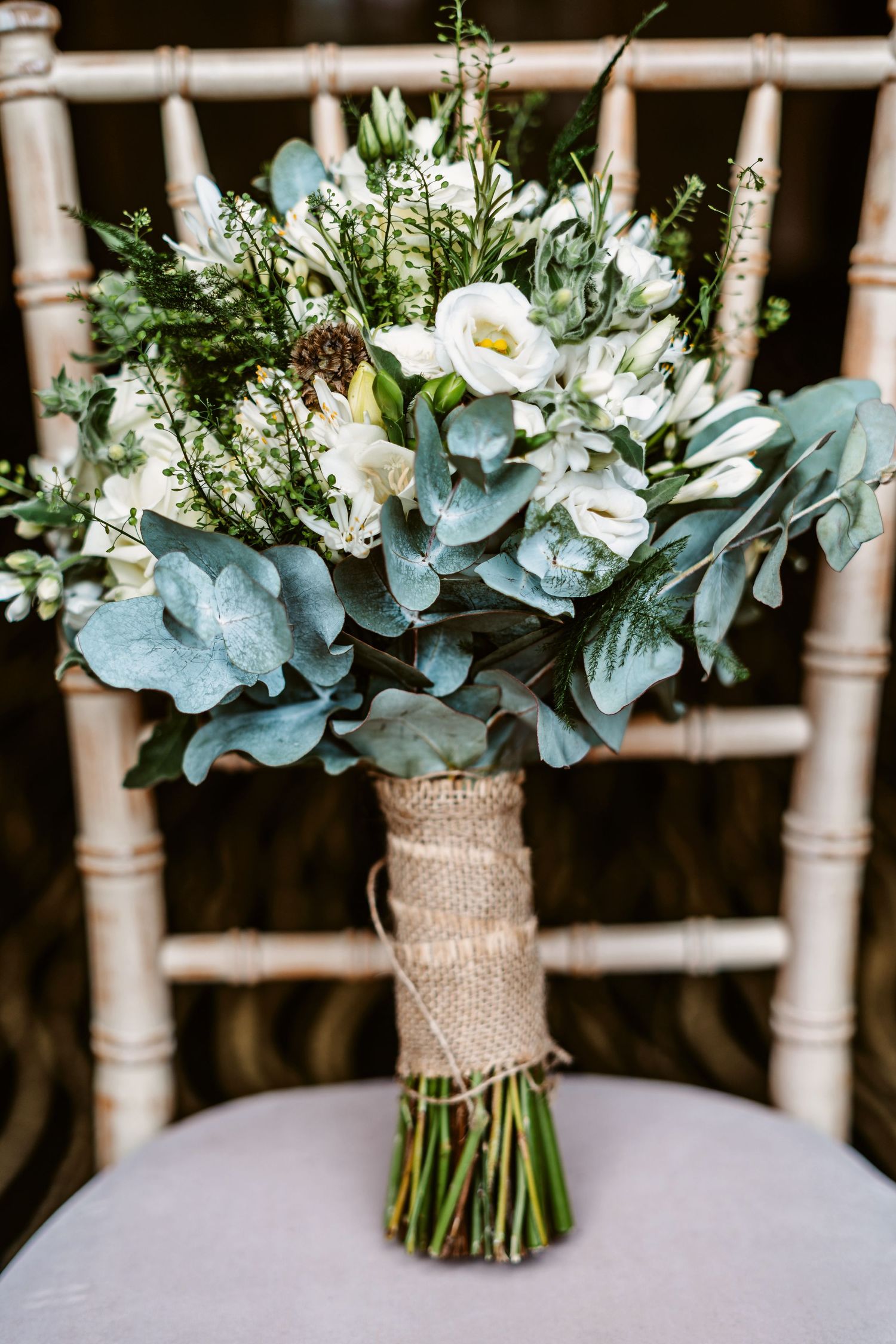 Elegant wedding bouquet with white flowers and dusty blue eucalyptus wrapped in burlap.