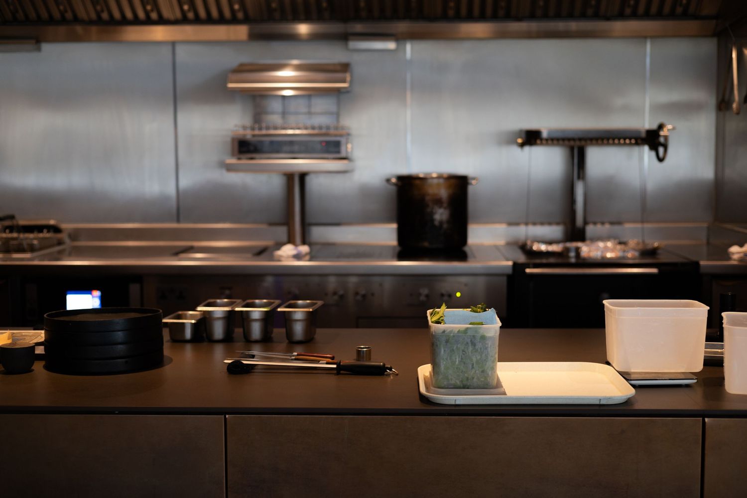Modern restaurant kitchen counter with stainless steel equipment and blue cocktail.