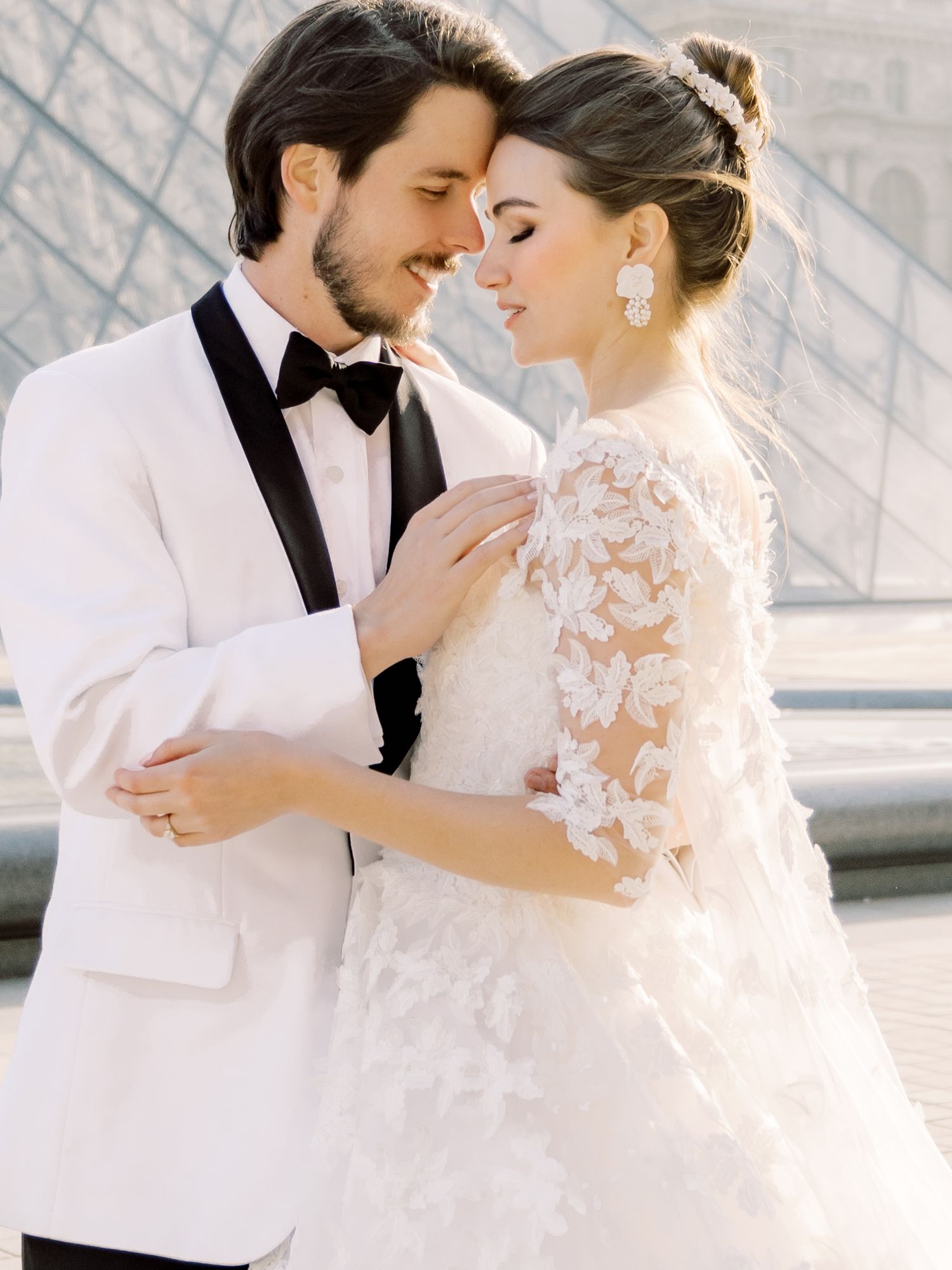 A tender wedding moment captured against modern architecture in soft lighting.