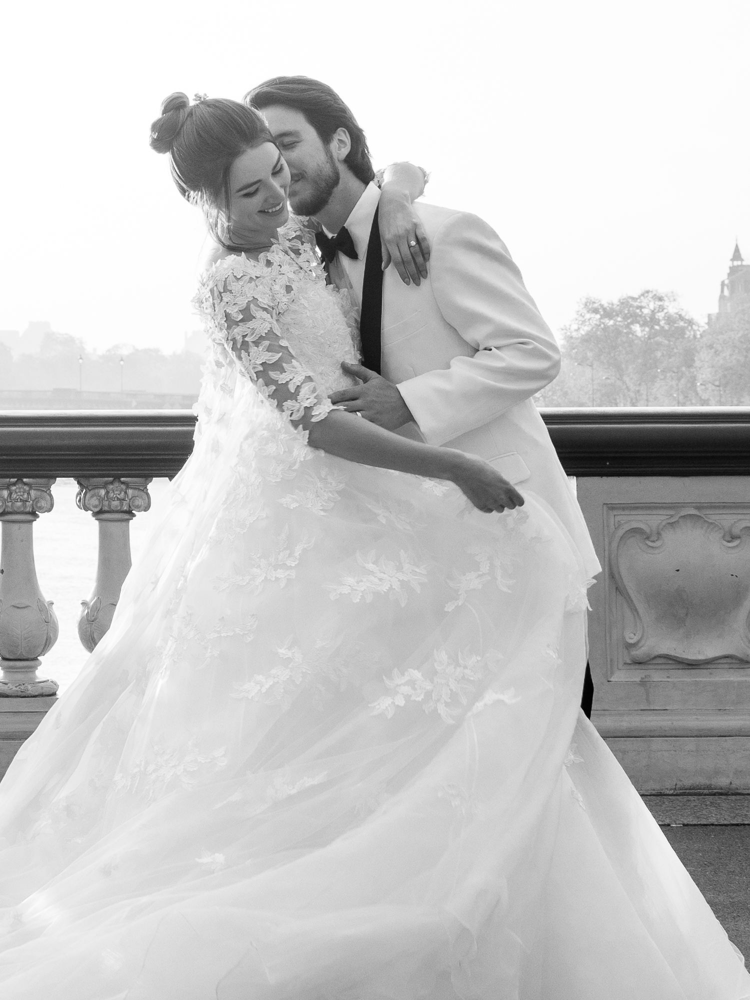A romantic wedding moment captured in black and white against an elegant balcony setting.