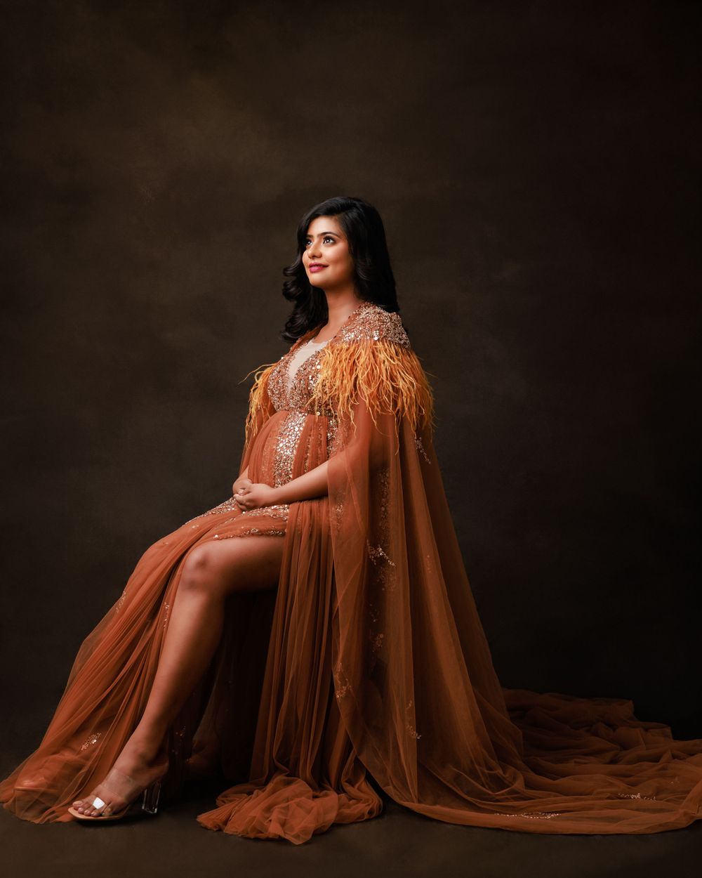 Maternity photo featuring flowing rust-colored dress with dramatic cape and slit detail.