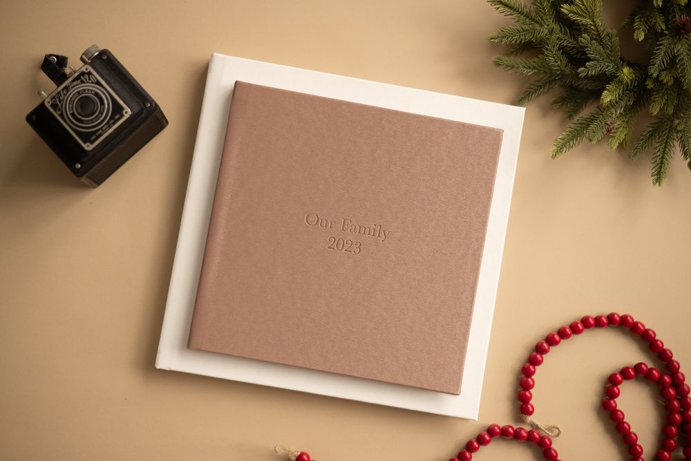 Decorative holiday display with evergreen branches and photo frames on warm beige surface.