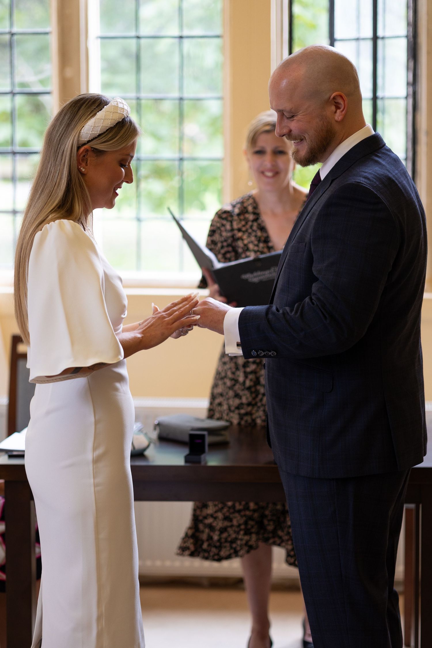 Couple exchanging rings during intimate indoor wedding ceremony.