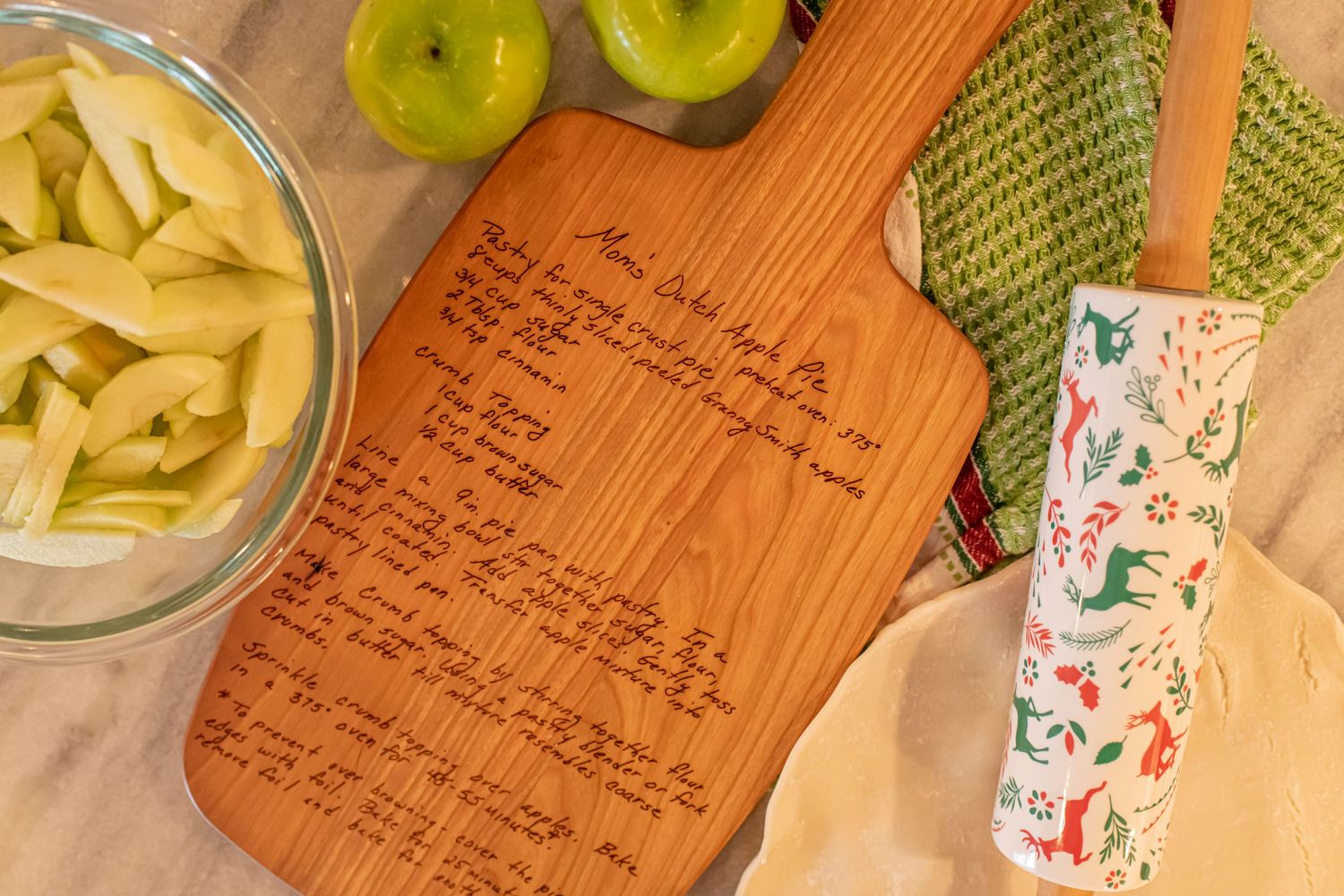 Wooden cutting board with recipe text alongside pasta, apples and kitchen accessories.