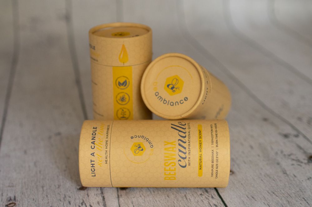 Collection of cylindrical beeswax candles with eco-friendly packaging stacked together.