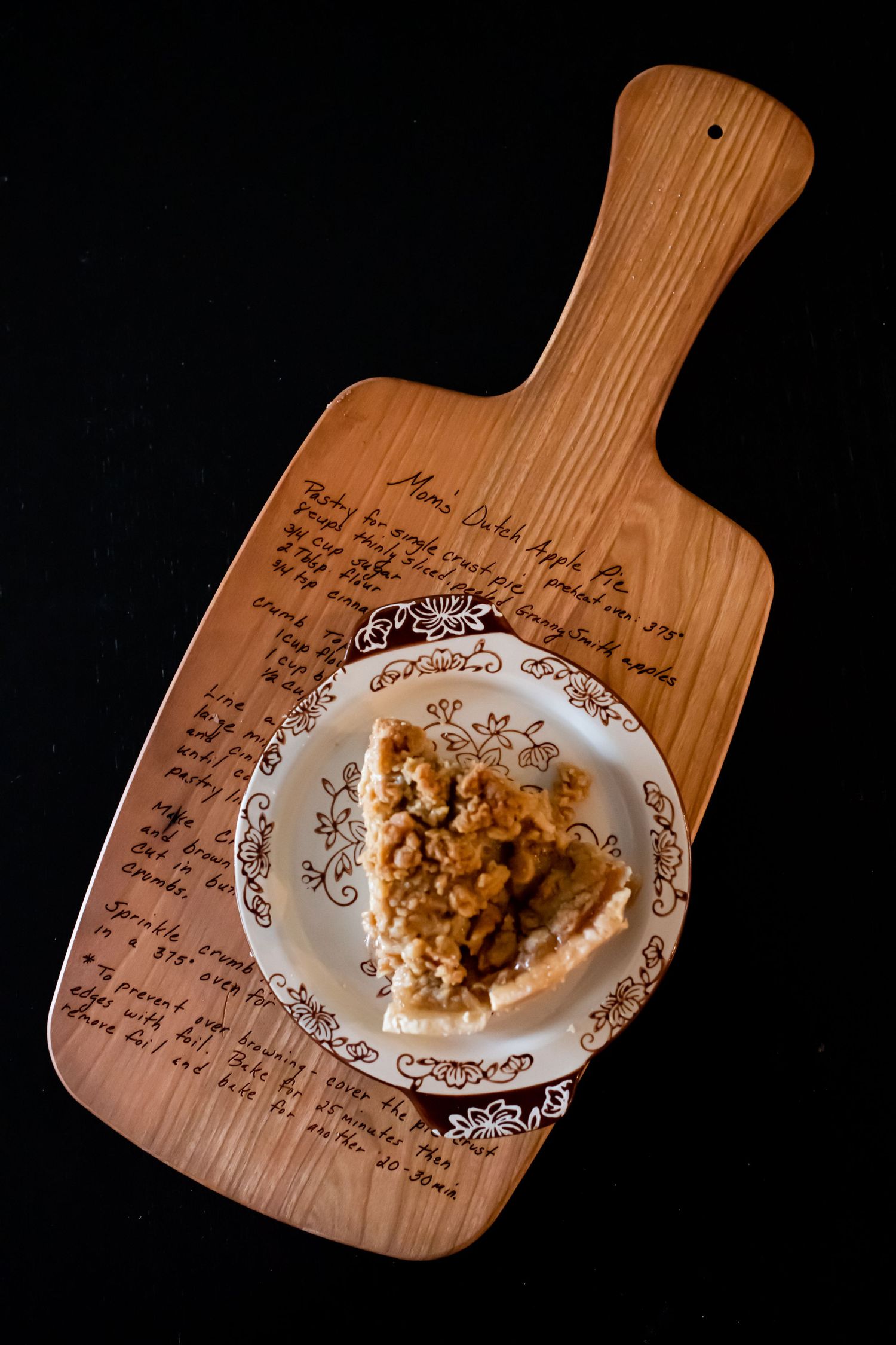 Slice of dessert on decorative plate atop wooden cutting board with handwritten recipe text.