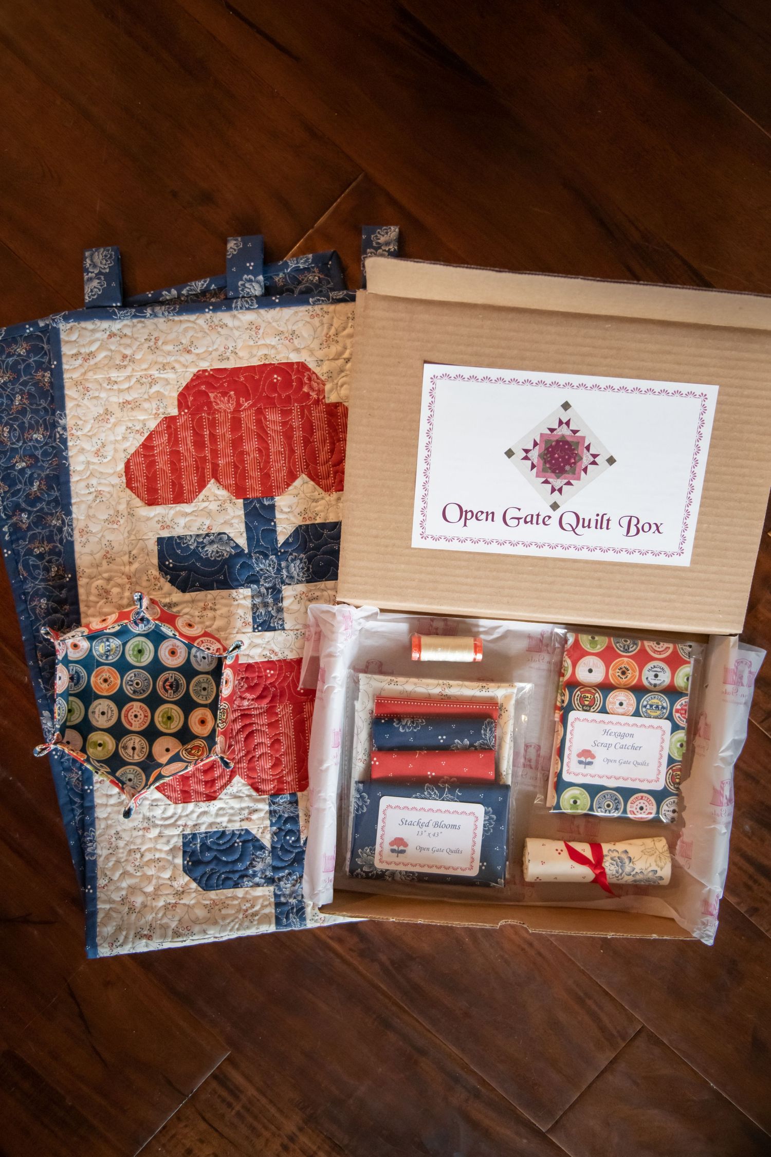 Red and blue floral quilt pattern with matching fabric materials and subscription box.