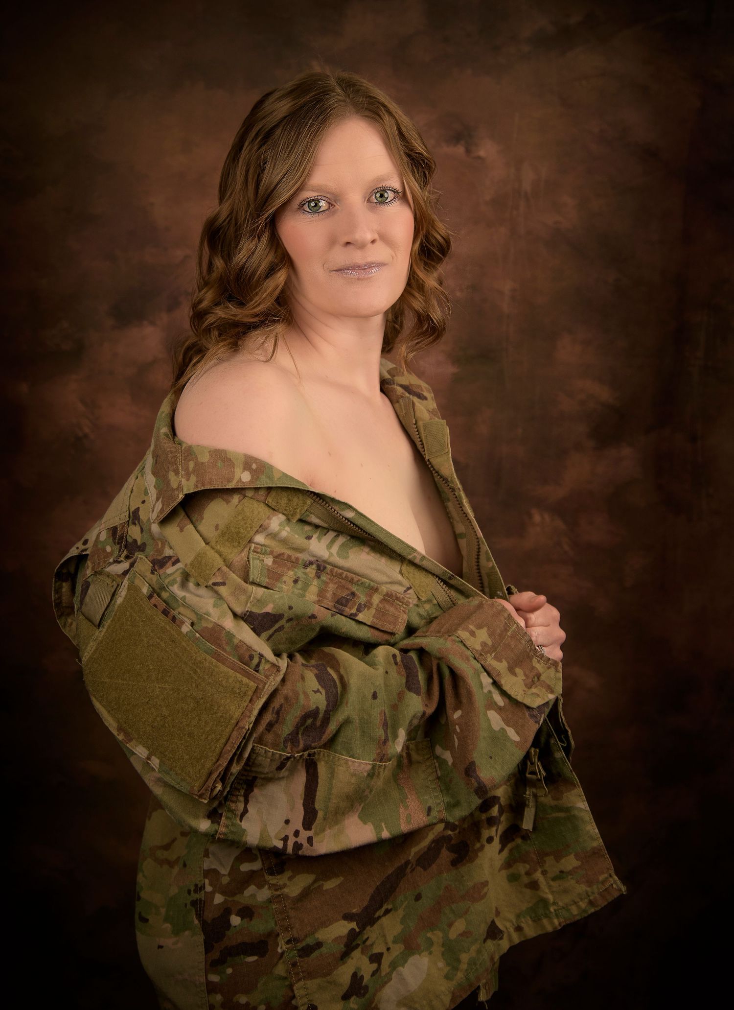 Portrait photo featuring someone wearing an open camouflage military uniform jacket against a dark brown backdrop.