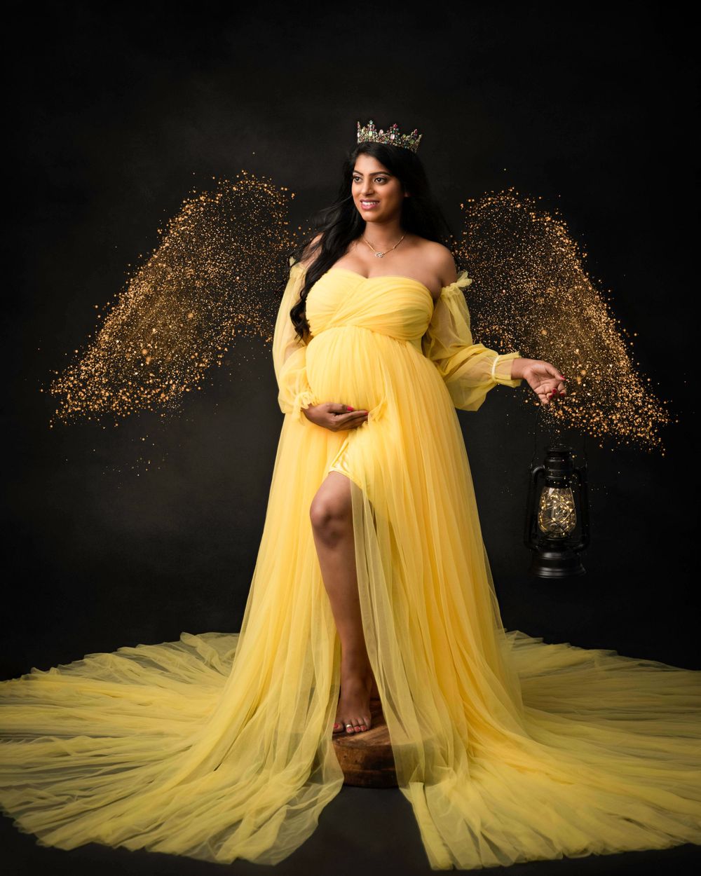Fantasy maternity portrait with yellow gown and glitter wing effect.