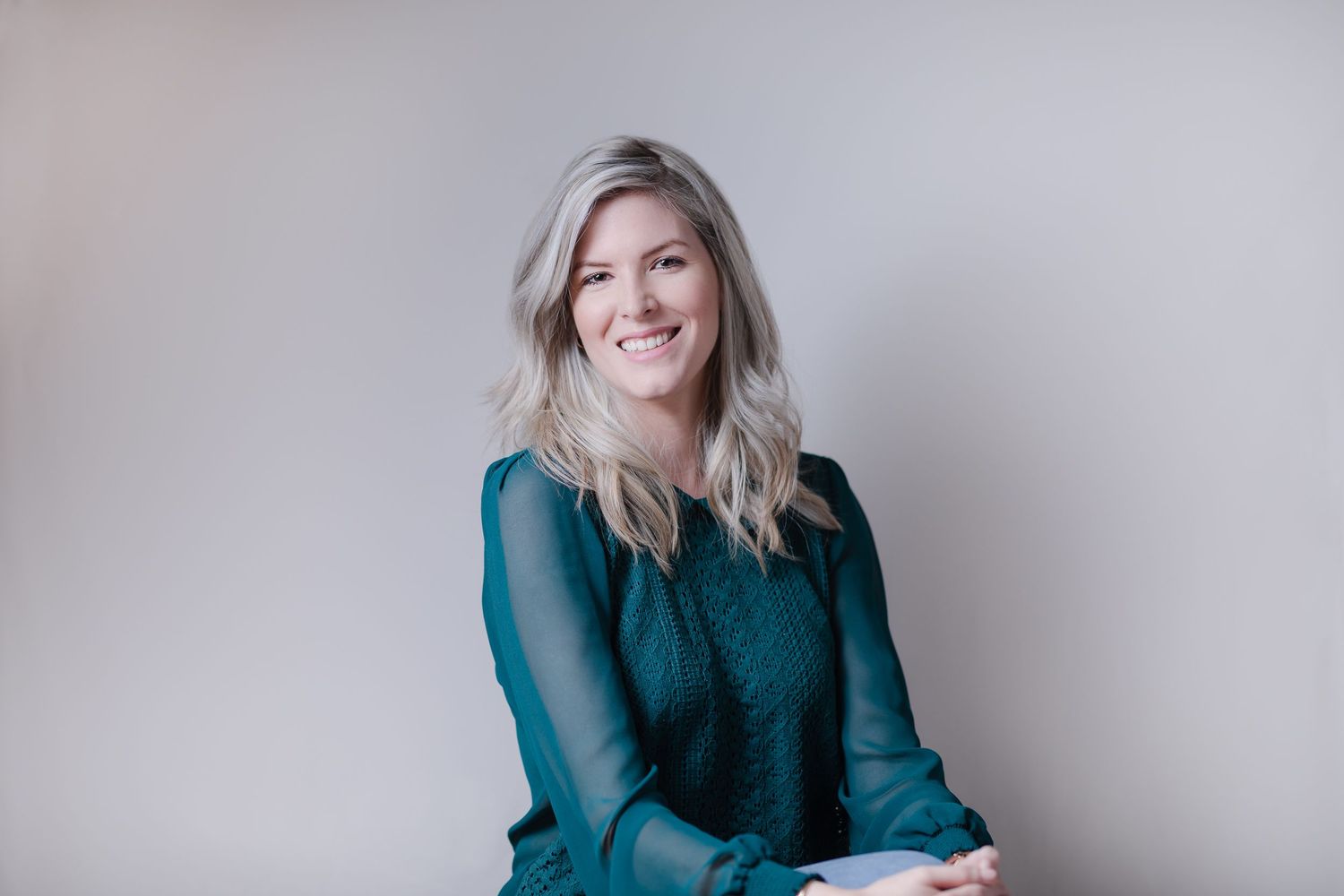 Portrait of person in teal sweater against neutral background.