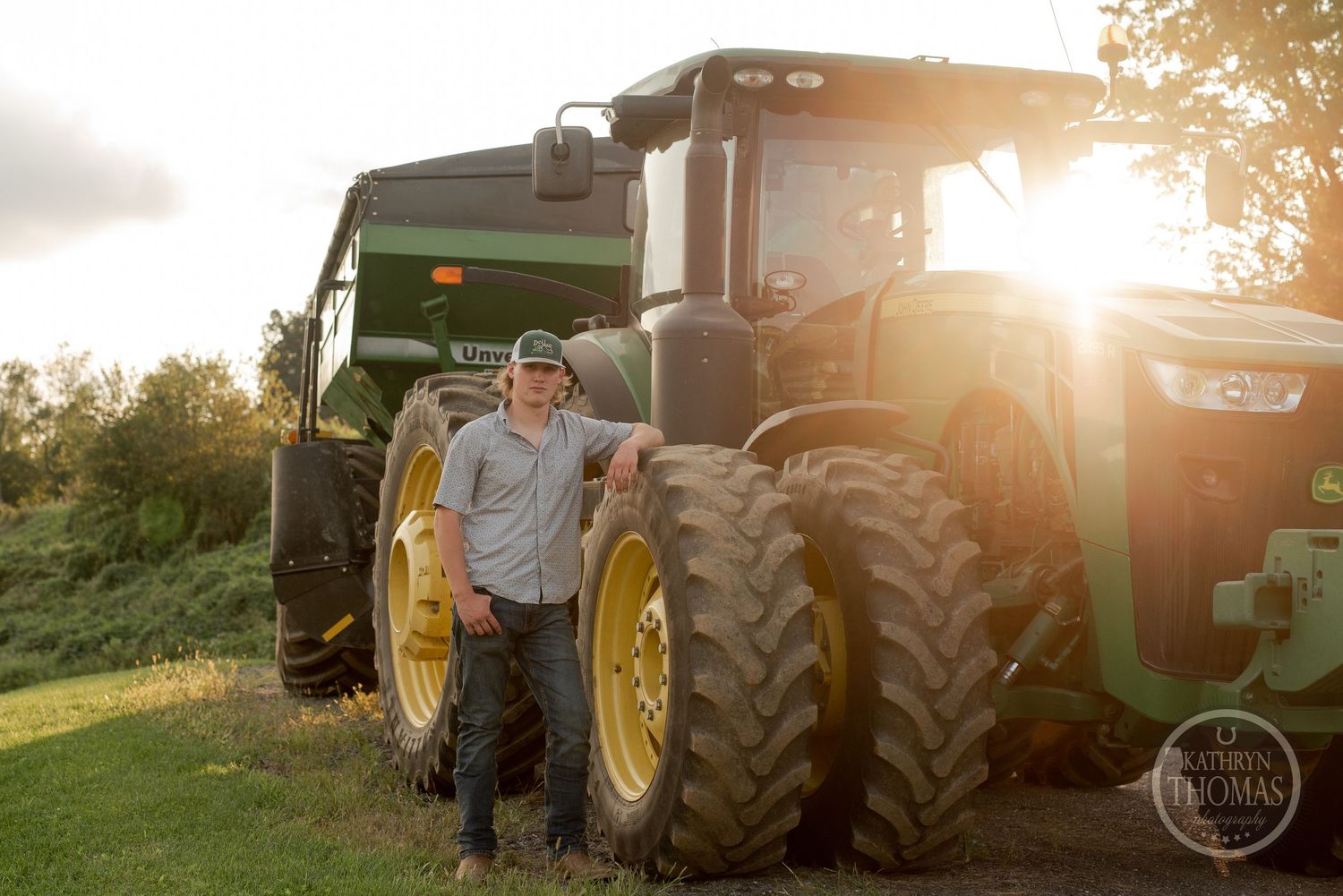 Large John Deere tractor parked on hillside during golden hour.