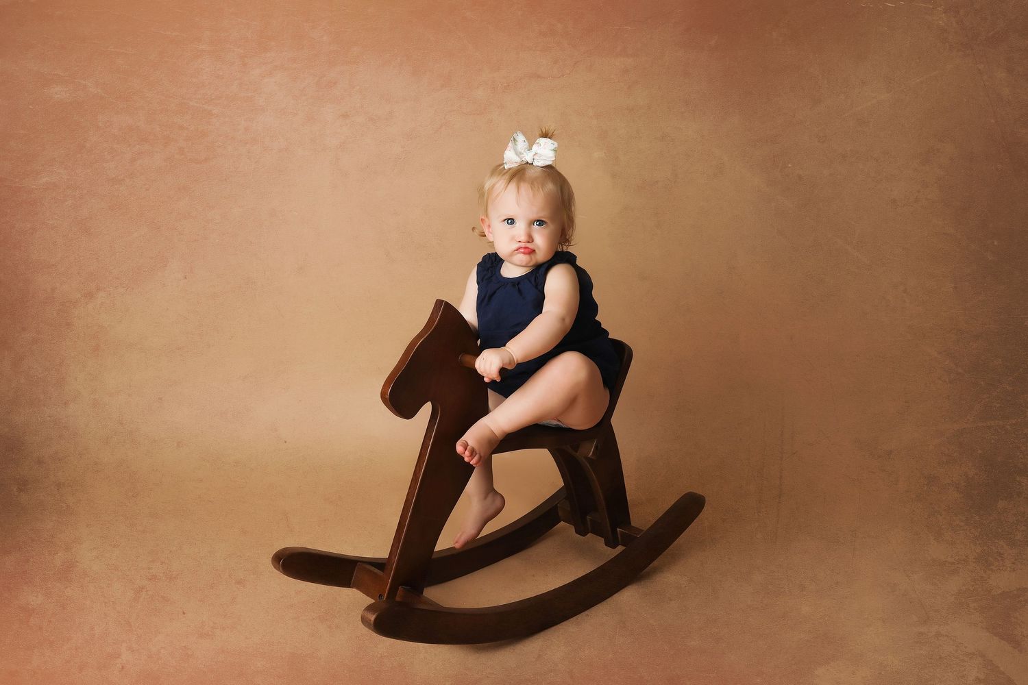 Baby frowning while sitting on a rocking horse