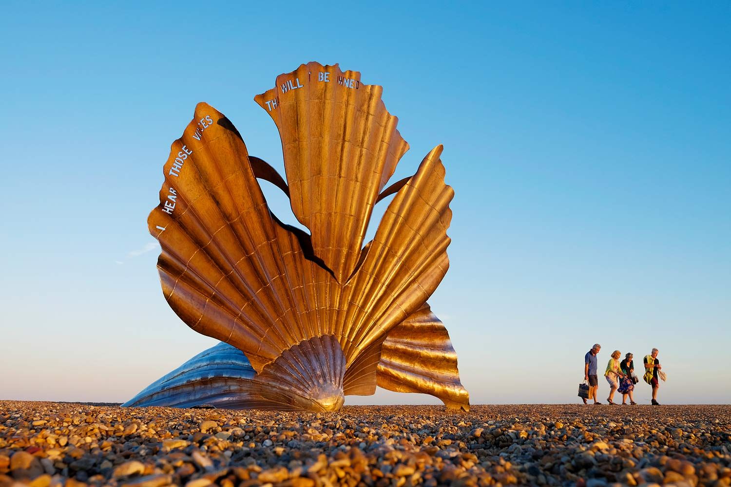 Tourists walking by the Aldeburgh Scallop on a summers day.