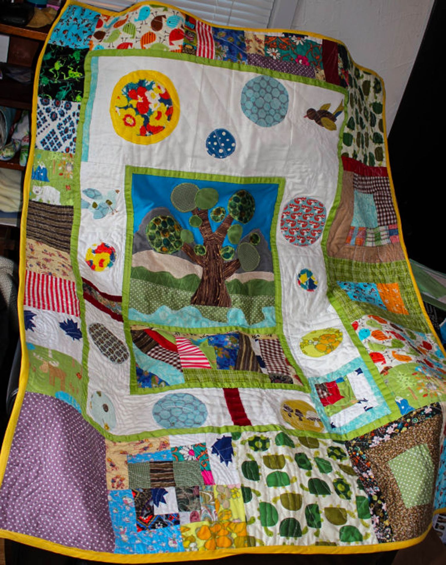Love quilt made with fabrics from many people showcases a tree and lots of circles.