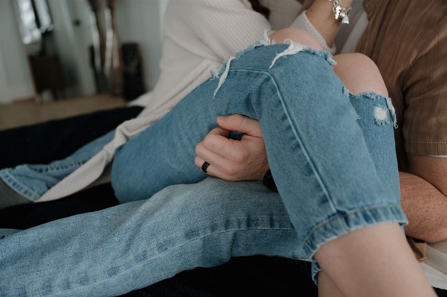 Close-up detail of distressed denim jeans and casual clothing during an intimate moment.