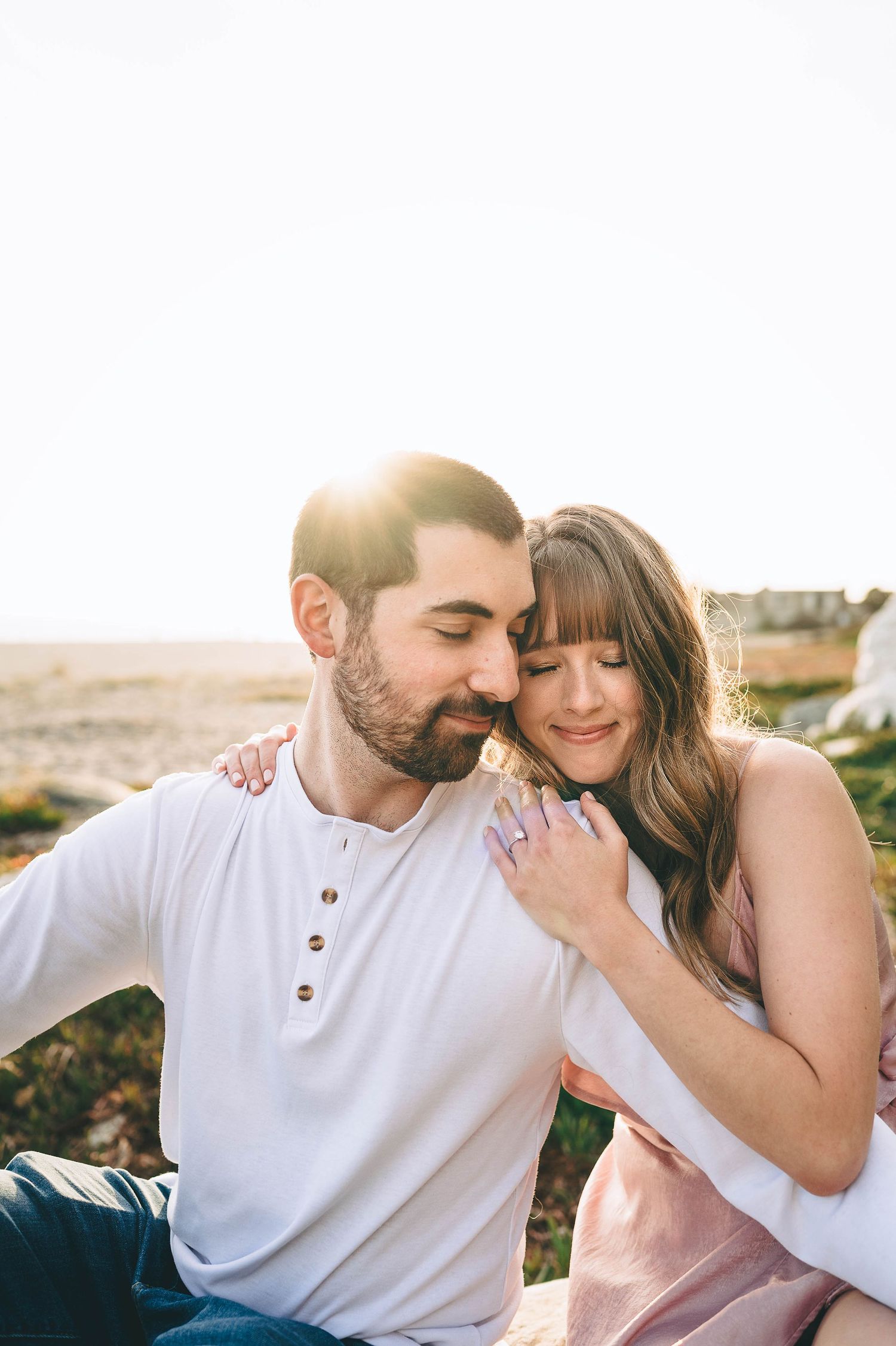 Intimate couple shares tender moment in natural sunlight outdoors.
