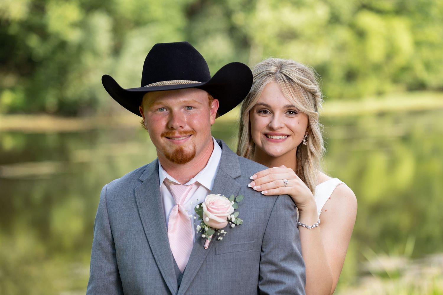 A cowboy and his new bride are all smiles in front of a pretty little Illinois pond outside of Effingham.