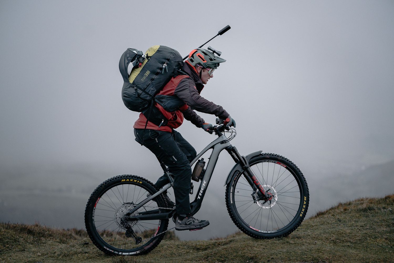 Mountain biker in full gear riding on misty terrain during overcast conditions.